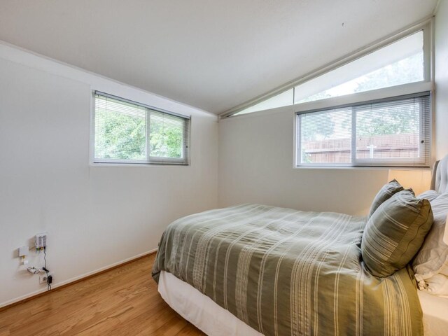 bedroom with wood finished floors and vaulted ceiling