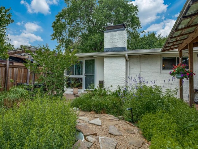 view of side of property with fence, a chimney, and brick siding