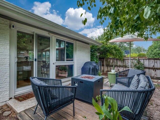 wooden deck with fence, an outdoor living space with a fire pit, and grilling area