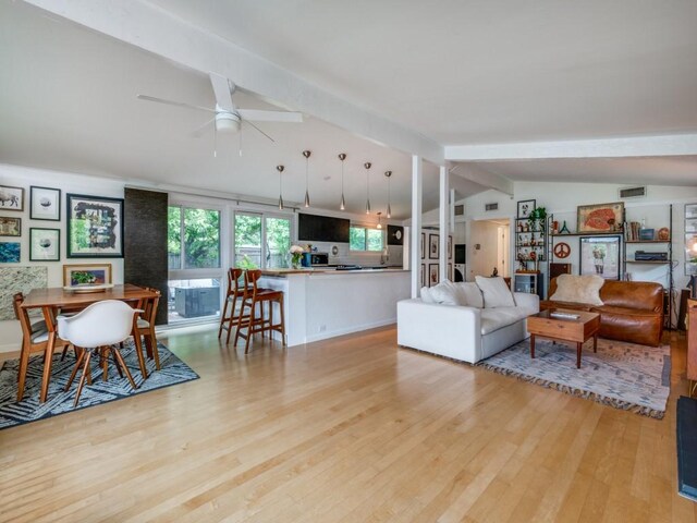 living area featuring lofted ceiling with beams, a ceiling fan, light wood-style flooring, and visible vents