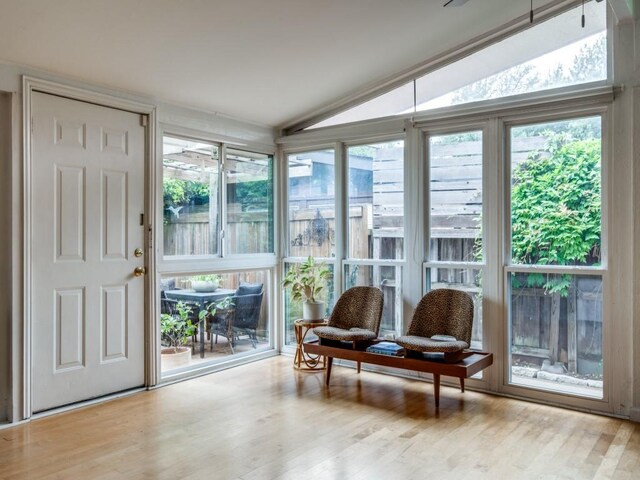 sunroom with a wealth of natural light, wood finished floors, and lofted ceiling