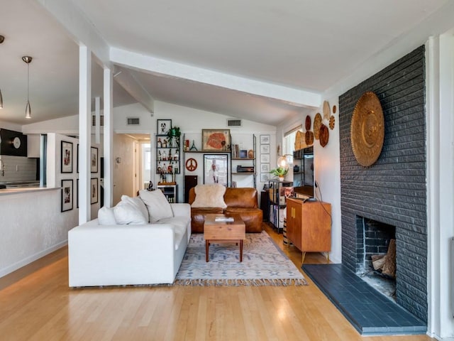 living room with visible vents, vaulted ceiling with beams, wood finished floors, and a fireplace