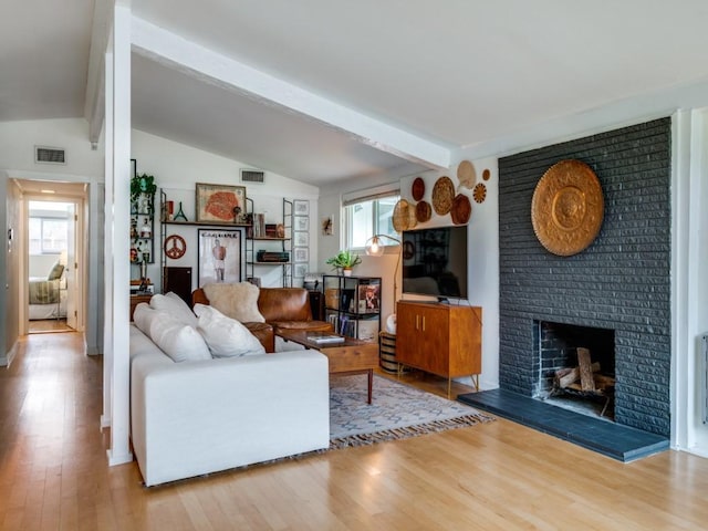 living room with plenty of natural light, lofted ceiling with beams, wood finished floors, and visible vents