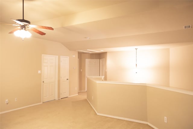 spare room featuring light colored carpet, a ceiling fan, baseboards, vaulted ceiling, and visible vents