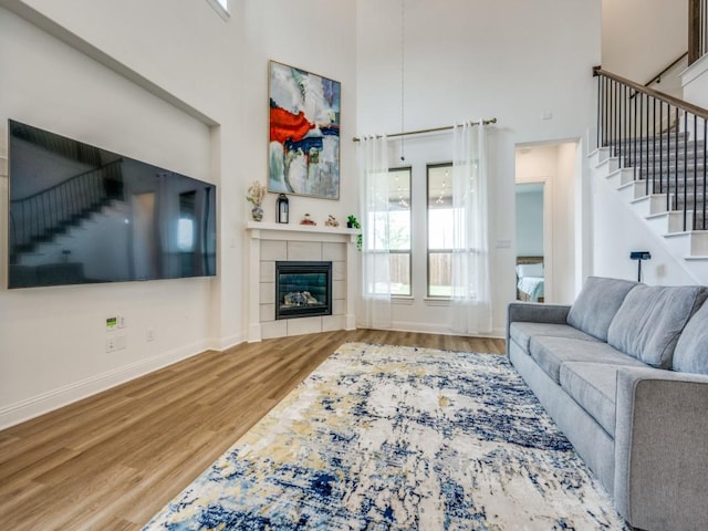 2513 Silver Leaf Dr, Northlake, TX 76226 - living area featuring wood finished floors, a tile fireplace, baseboards, a high ceiling, and stairs