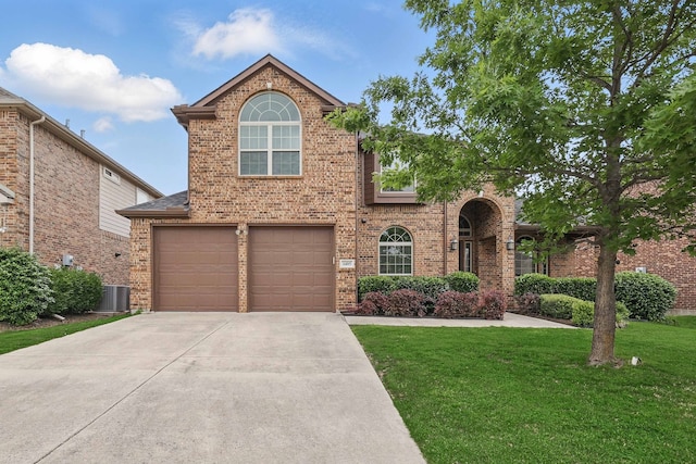 traditional-style house with brick siding, a front lawn, an attached garage, and driveway