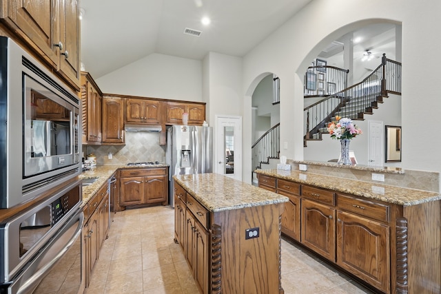 kitchen with visible vents, a kitchen island, high vaulted ceiling, appliances with stainless steel finishes, and backsplash