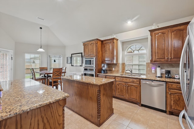 kitchen with decorative backsplash, light stone countertops, a sink, appliances with stainless steel finishes, and vaulted ceiling