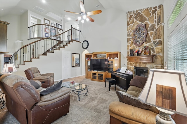 carpeted living room featuring a ceiling fan, visible vents, a fireplace, stairway, and high vaulted ceiling