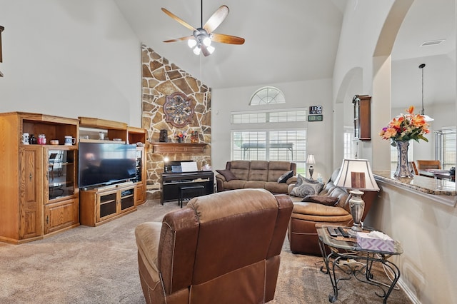living area featuring ceiling fan, visible vents, arched walkways, high vaulted ceiling, and light carpet