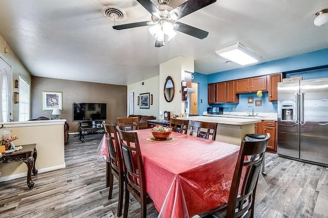 dining space with visible vents, light wood finished floors, ceiling fan, and baseboards