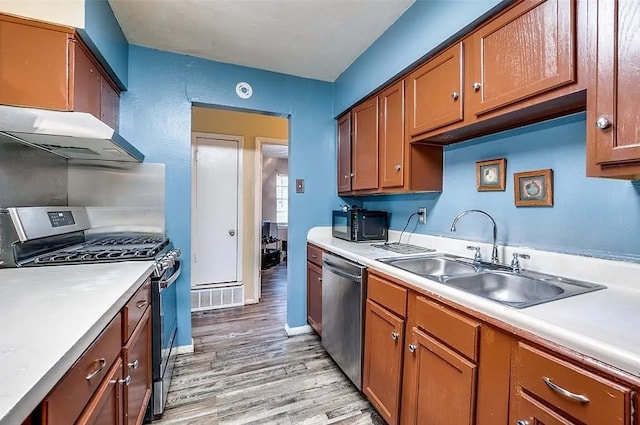 kitchen with light countertops, stainless steel appliances, a sink, and light wood-style floors