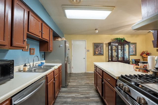kitchen with brown cabinets, a sink, light countertops, stainless steel appliances, and dark wood-style floors