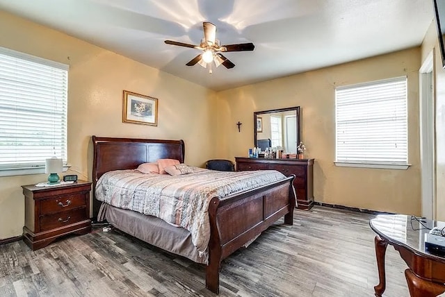 bedroom featuring a ceiling fan, multiple windows, and wood finished floors