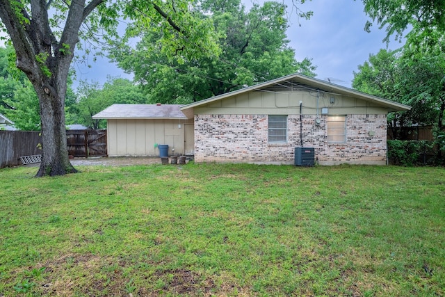 view of side of home with brick siding, fence, and a yard