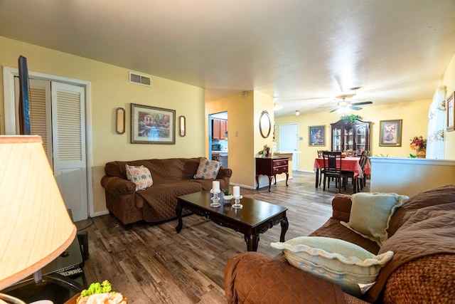 living room featuring a ceiling fan, baseboards, visible vents, and wood finished floors