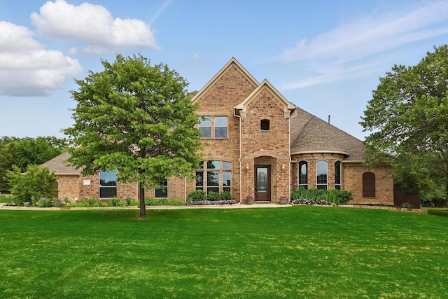 traditional-style home with brick siding, a shingled roof, and a front yard