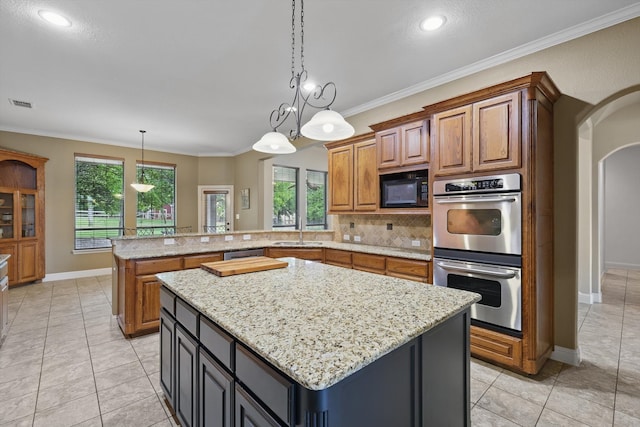 kitchen featuring a sink, brown cabinetry, stainless steel appliances, a peninsula, and visible vents