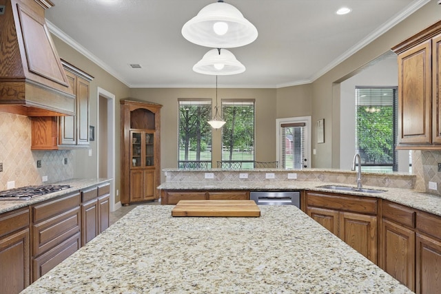 kitchen with brown cabinets, light stone countertops, appliances with stainless steel finishes, a sink, and custom exhaust hood