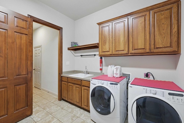 laundry area featuring a sink, light tile patterned floors, independent washer and dryer, and cabinet space