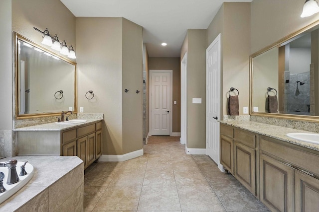bathroom featuring a garden tub, a tile shower, two vanities, a sink, and baseboards