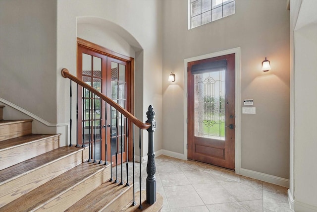 foyer entrance with baseboards, stairs, light tile patterned flooring, and a wealth of natural light