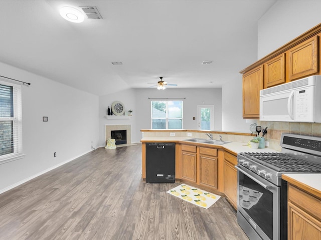 kitchen with gas range, a sink, white microwave, a peninsula, and black dishwasher