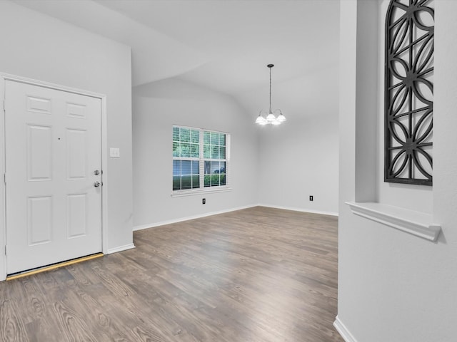 foyer entrance featuring an inviting chandelier, baseboards, vaulted ceiling, and wood finished floors