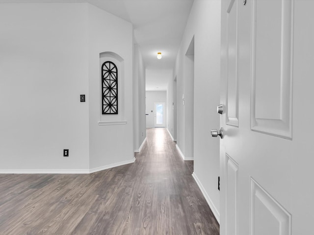 corridor featuring baseboards and dark wood finished floors
