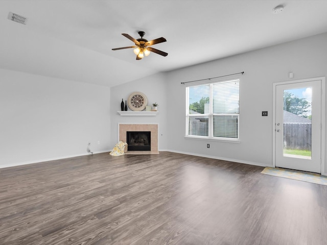 unfurnished living room with a tiled fireplace, a ceiling fan, wood finished floors, and visible vents