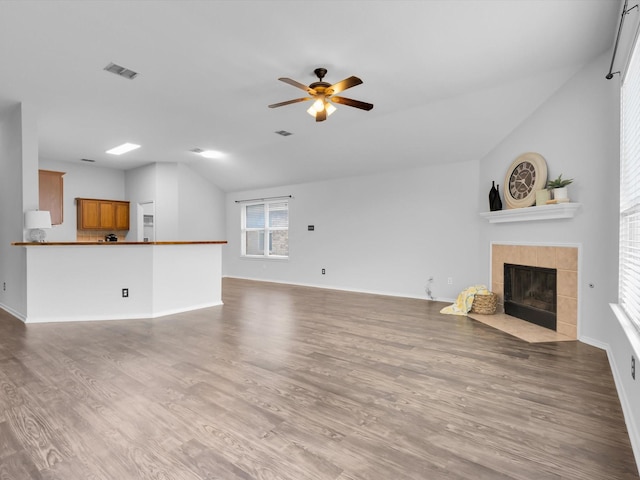 unfurnished living room featuring visible vents, wood finished floors, a fireplace, baseboards, and a ceiling fan