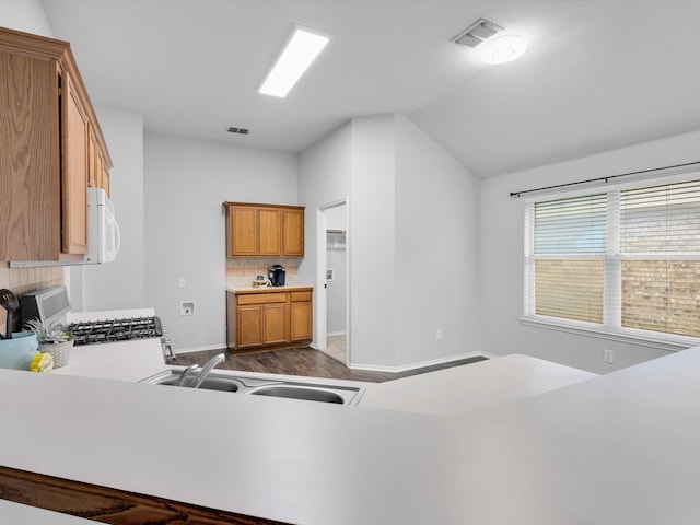 kitchen featuring visible vents, vaulted ceiling, brown cabinets, white microwave, and dark wood-style floors