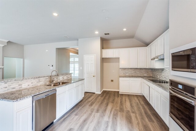 kitchen with white cabinets, a sink, light wood-style flooring, stainless steel appliances, and decorative backsplash