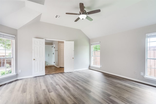 interior space with multiple windows, vaulted ceiling, wood finished floors, and visible vents