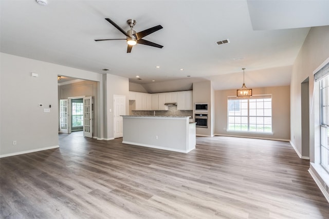 unfurnished living room featuring ceiling fan, lofted ceiling, wood finished floors, and visible vents