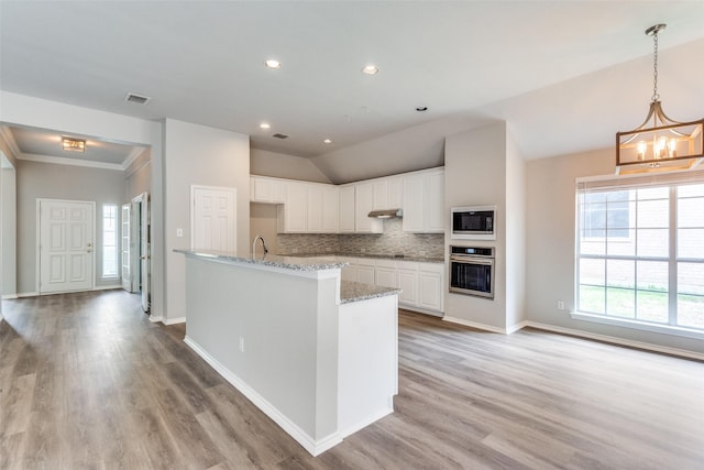 kitchen featuring an inviting chandelier, stainless steel oven, built in microwave, and a healthy amount of sunlight