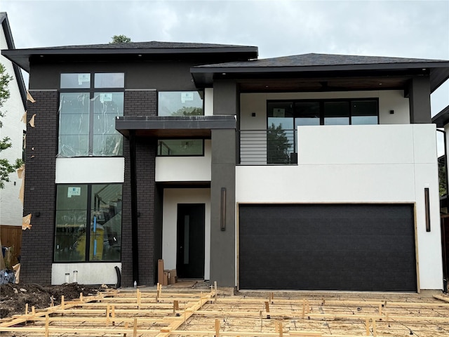 view of front of home featuring brick siding, a balcony, and stucco siding