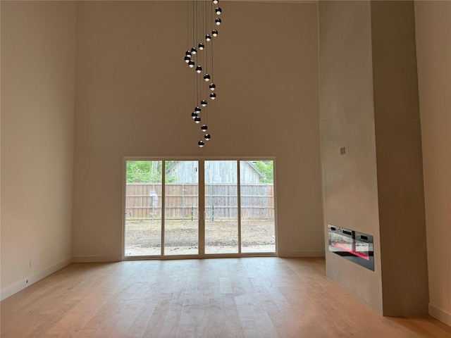 spare room featuring baseboards, plenty of natural light, and a towering ceiling