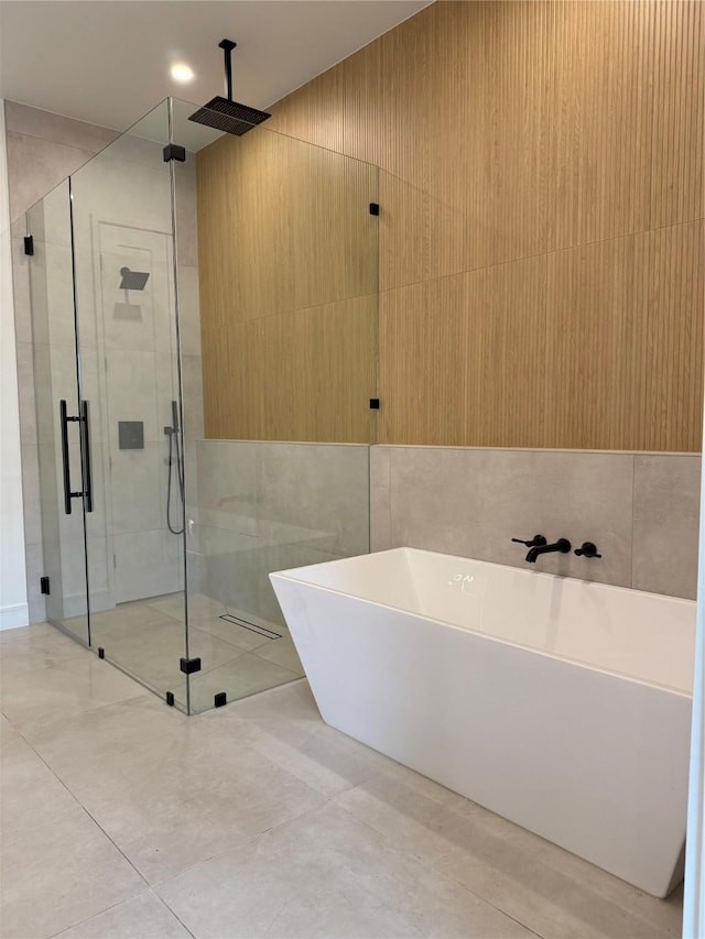 bathroom with tile patterned floors, a stall shower, tile walls, and a soaking tub