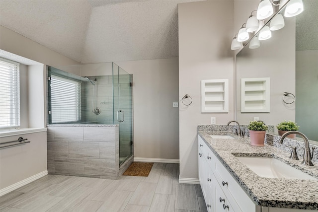 full bath with a textured ceiling, baseboards, a sink, and a stall shower