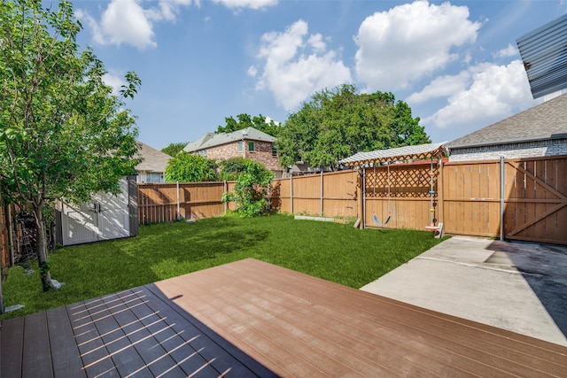 wooden deck with a storage shed, a gate, an outdoor structure, a fenced backyard, and a yard
