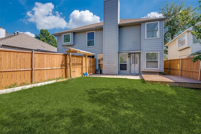 rear view of property with a pergola, a deck, a fenced backyard, a chimney, and a lawn