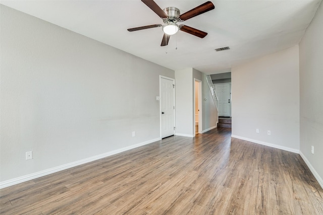 spare room featuring baseboards, ceiling fan, visible vents, and wood finished floors