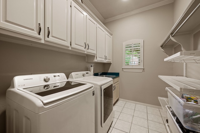 laundry area featuring cabinet space, ornamental molding, baseboards, light tile patterned floors, and washing machine and dryer