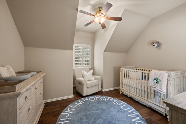 bedroom with a ceiling fan, baseboards, vaulted ceiling, and a crib