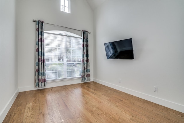 unfurnished room featuring baseboards, vaulted ceiling, and wood finished floors