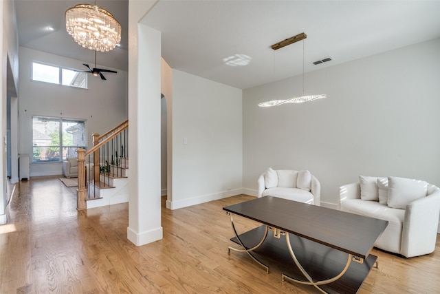 living area with stairs, baseboards, visible vents, and light wood finished floors