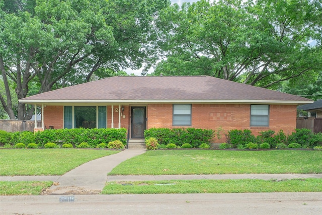 single story home featuring brick siding, a shingled roof, and a front lawn