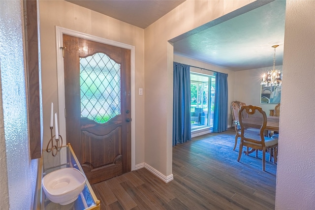 entrance foyer featuring baseboards, wood finished floors, and a notable chandelier