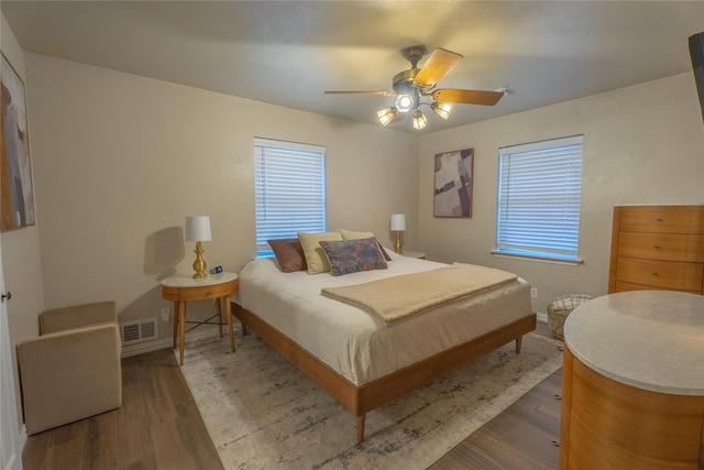 bedroom with multiple windows, wood finished floors, and visible vents